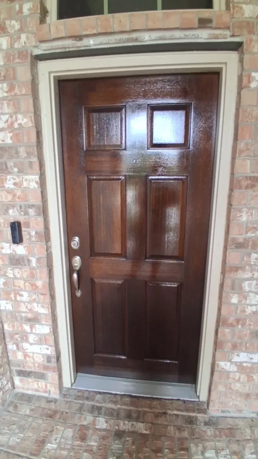 The same wood entry door with an even dark finish and uncovered hardware.