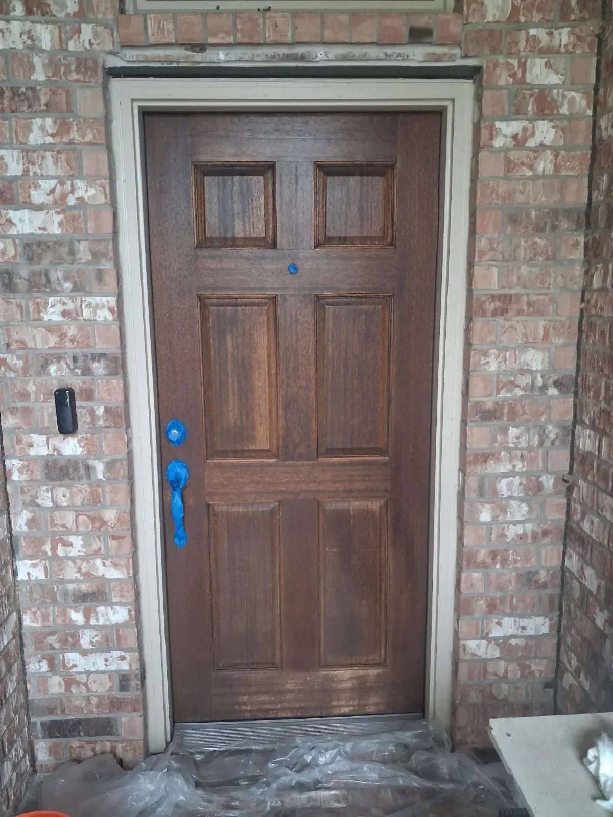 A wood entry door with its hardware masked during prep.
